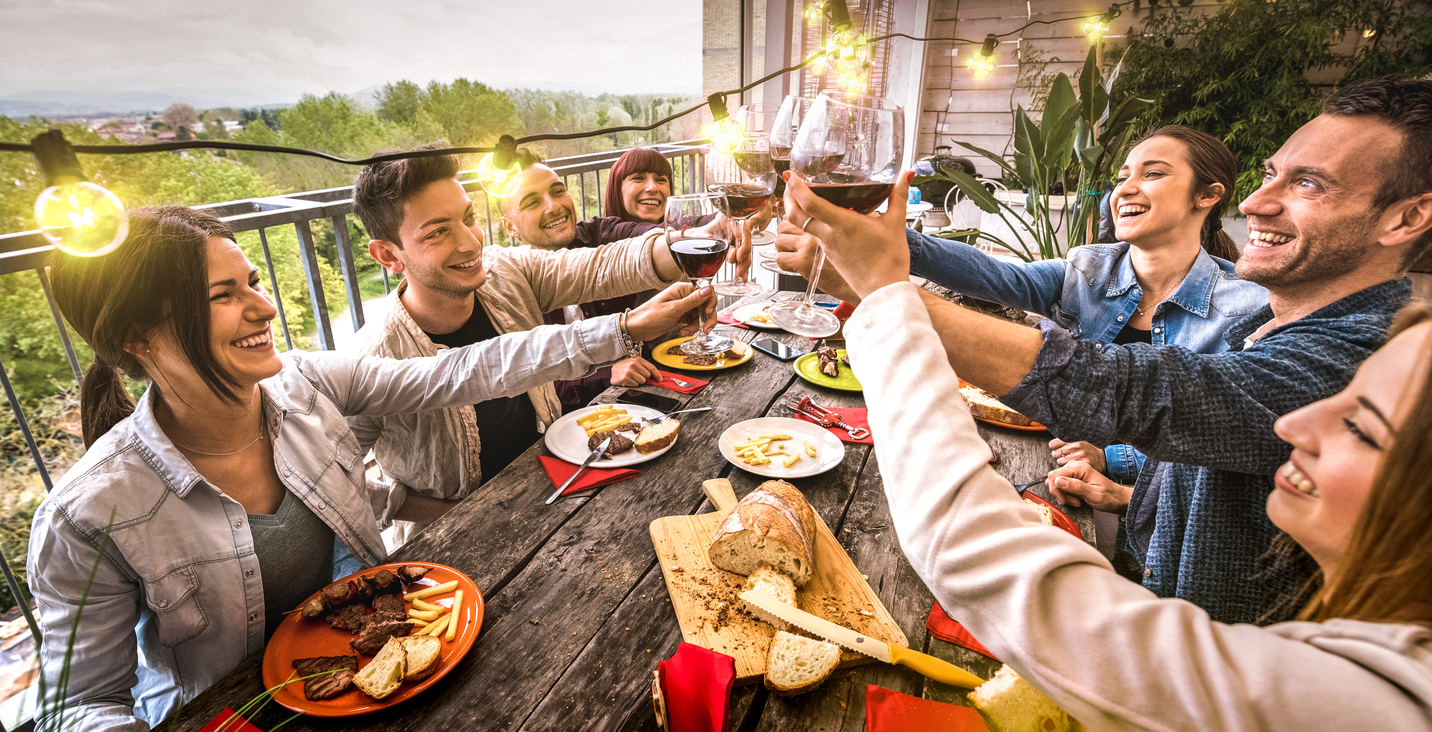 iStock-1187411357 short term rental renovations friends having dinner party on balcony with lights.jpg