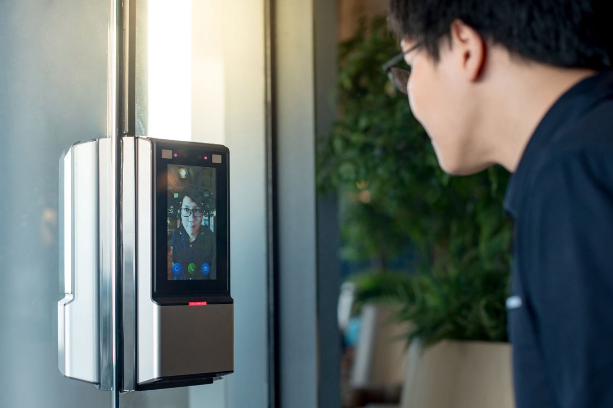 A person peers into the camera of a smart lock.