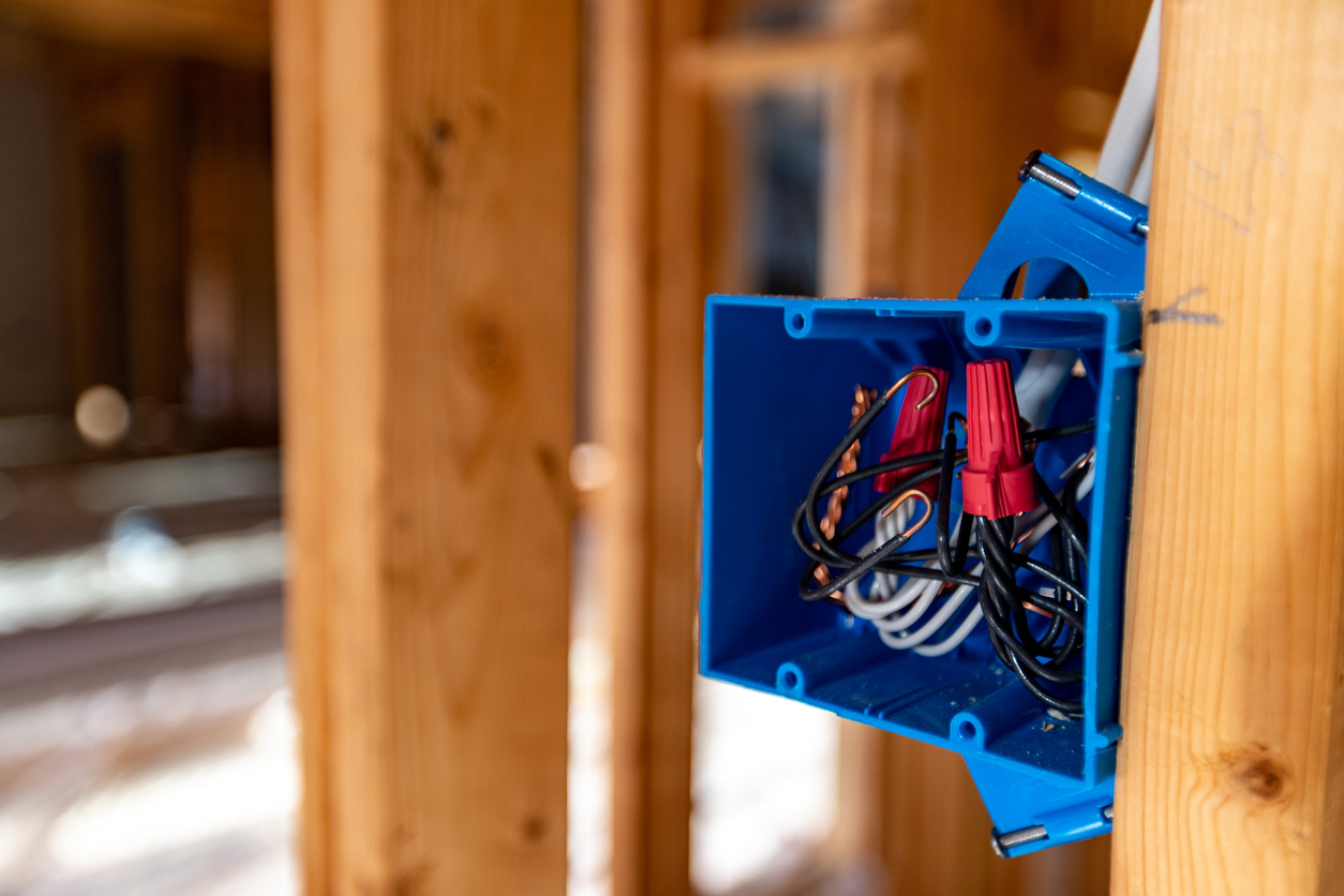 Blue electrical box attached to wood wall stud in home being built.