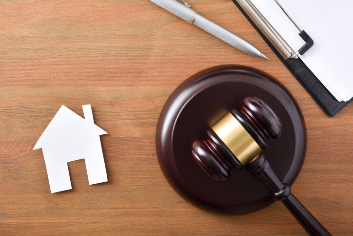 judges-gavel-and-clipboard-and-pen-next-to-symbol-for-house-on-wood-background