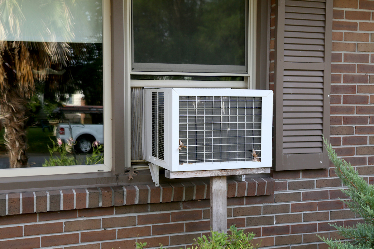 An air conditioner unit is installed in the window with a mounting rail underneath it.