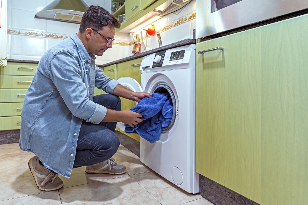 istock - 1367022943 -décoration d'une buanderie organisation d'un garde-manger homme mettant du linge dans le sèche-linge