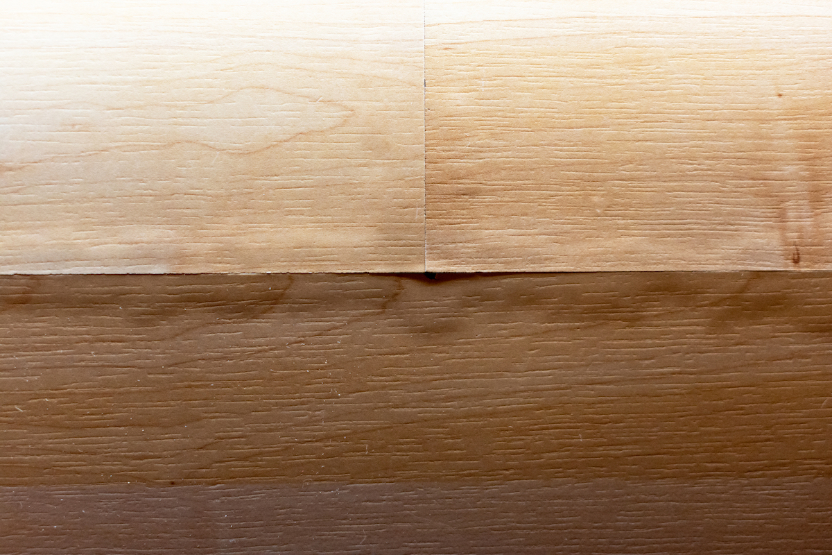 Faux wood laminate flooring planks are bubbling at the edges due to water damage.