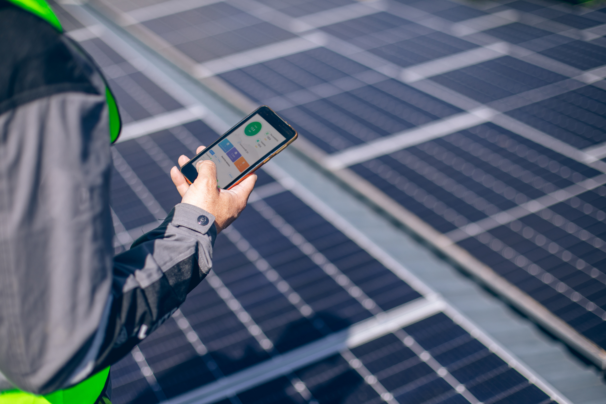 Man checks mobile app while standing in front of solar panels.