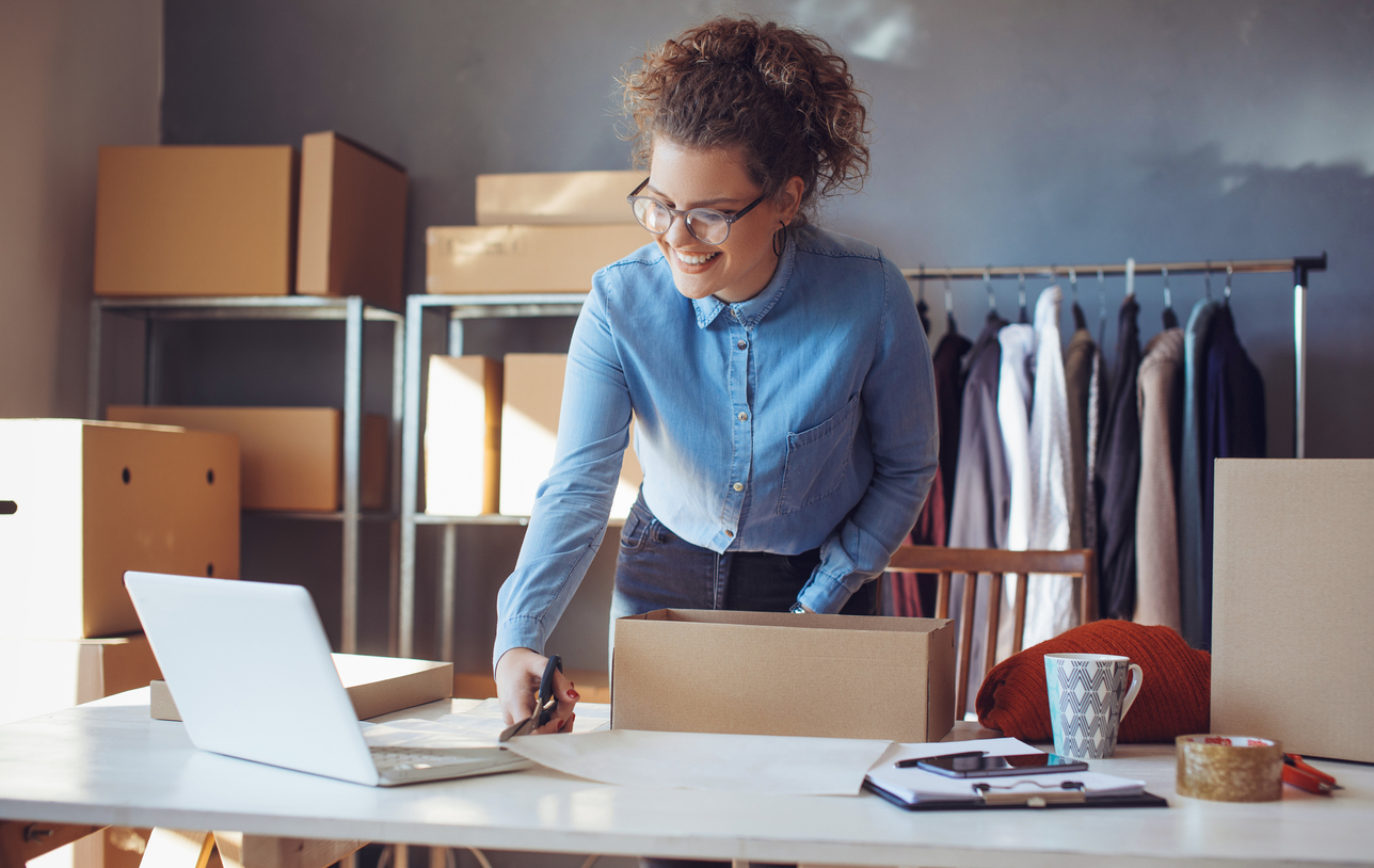 Small business owner. Women, owner of small business packing product in boxes preparing it for delivery.