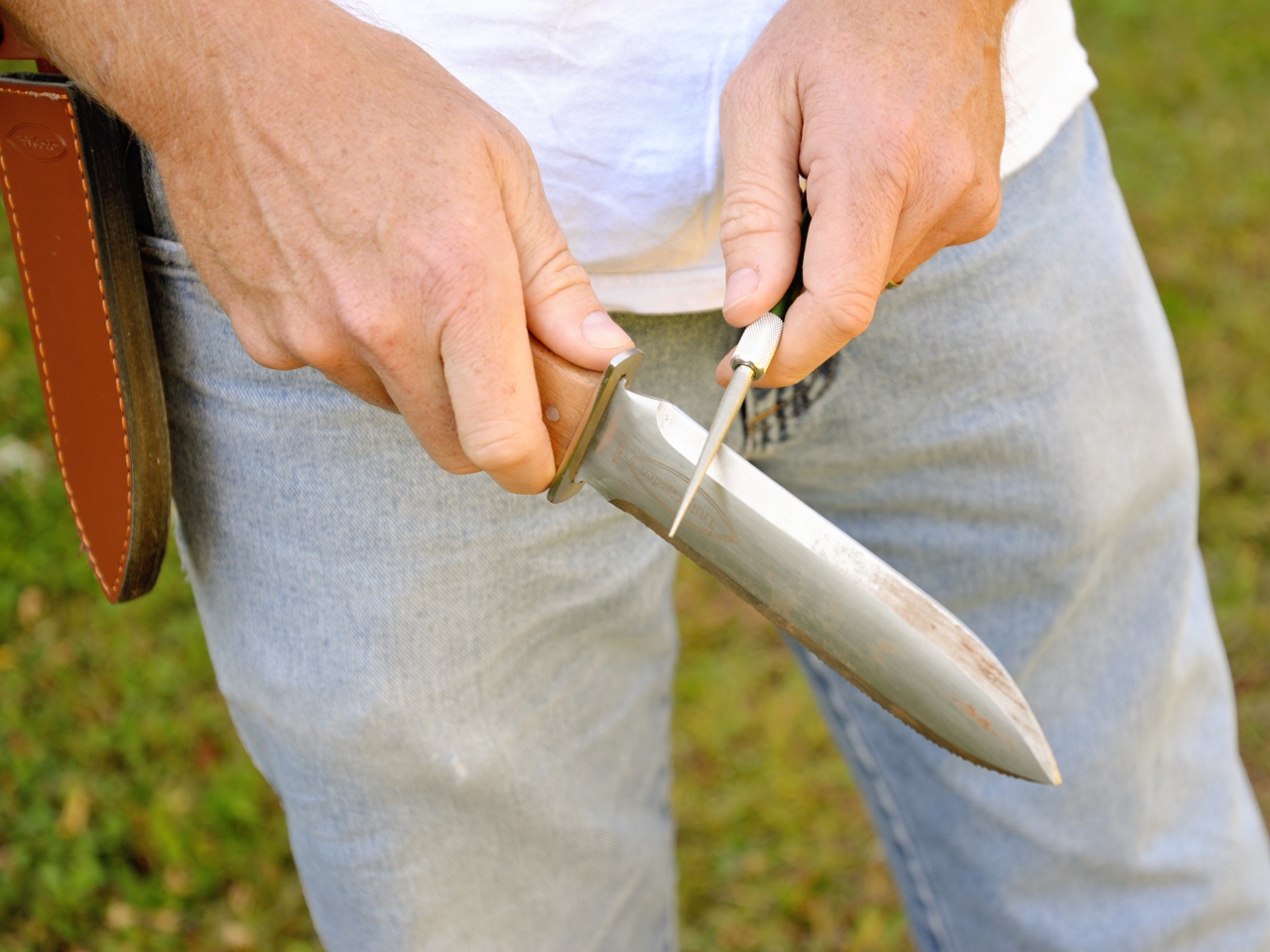 A person using the included sharpening rod to sharpen the Truly Garden hori hori knife.