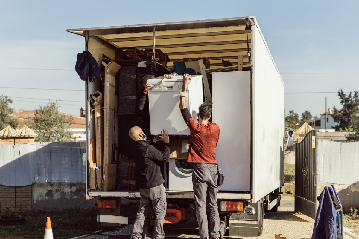 Two movers loading washer on truck.