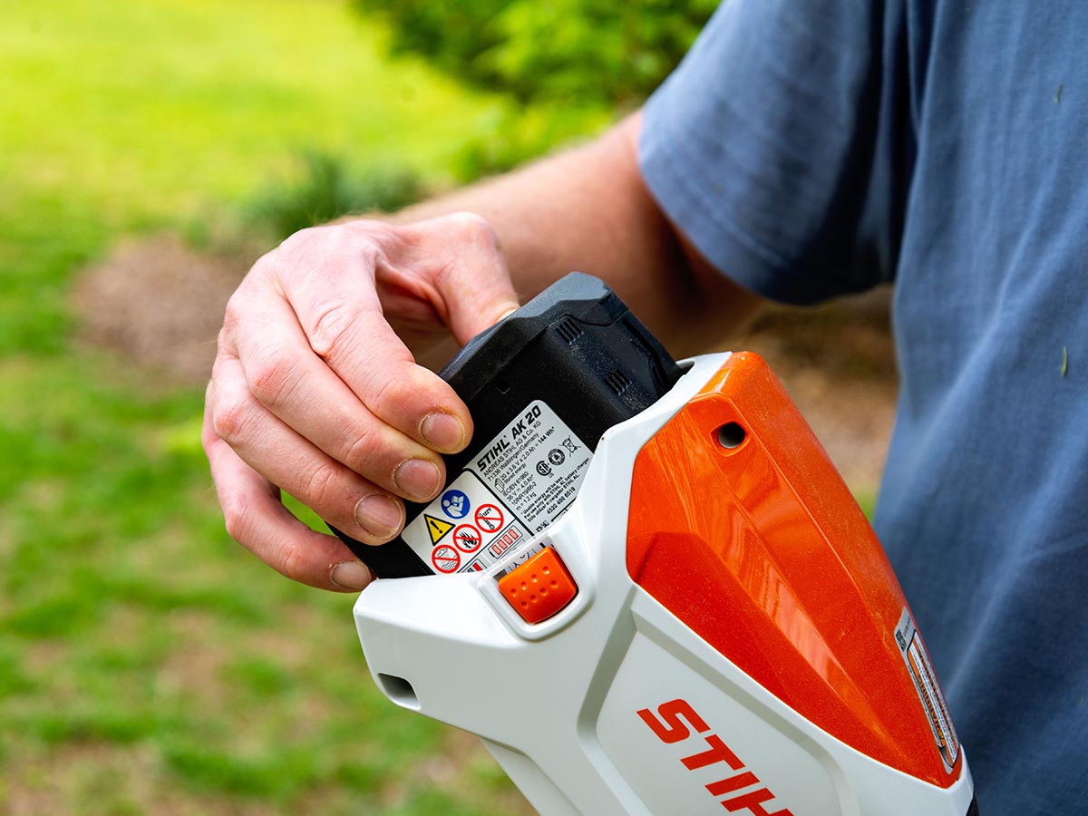 Personne mettant la batterie dans la débroussailleuse Stihl FSA 80 R