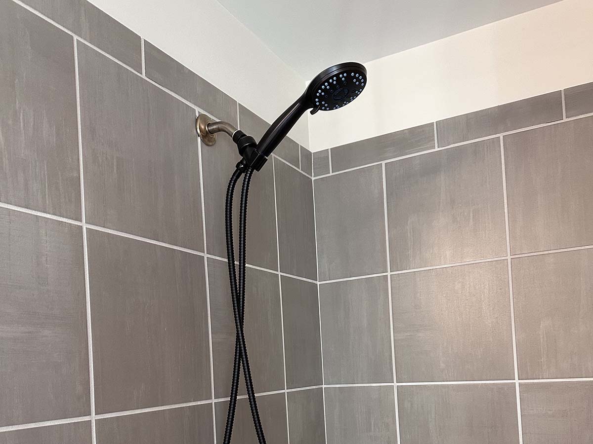 Pommeau de douche noir mat monté sur un carrelage carré taupe à grande échelle