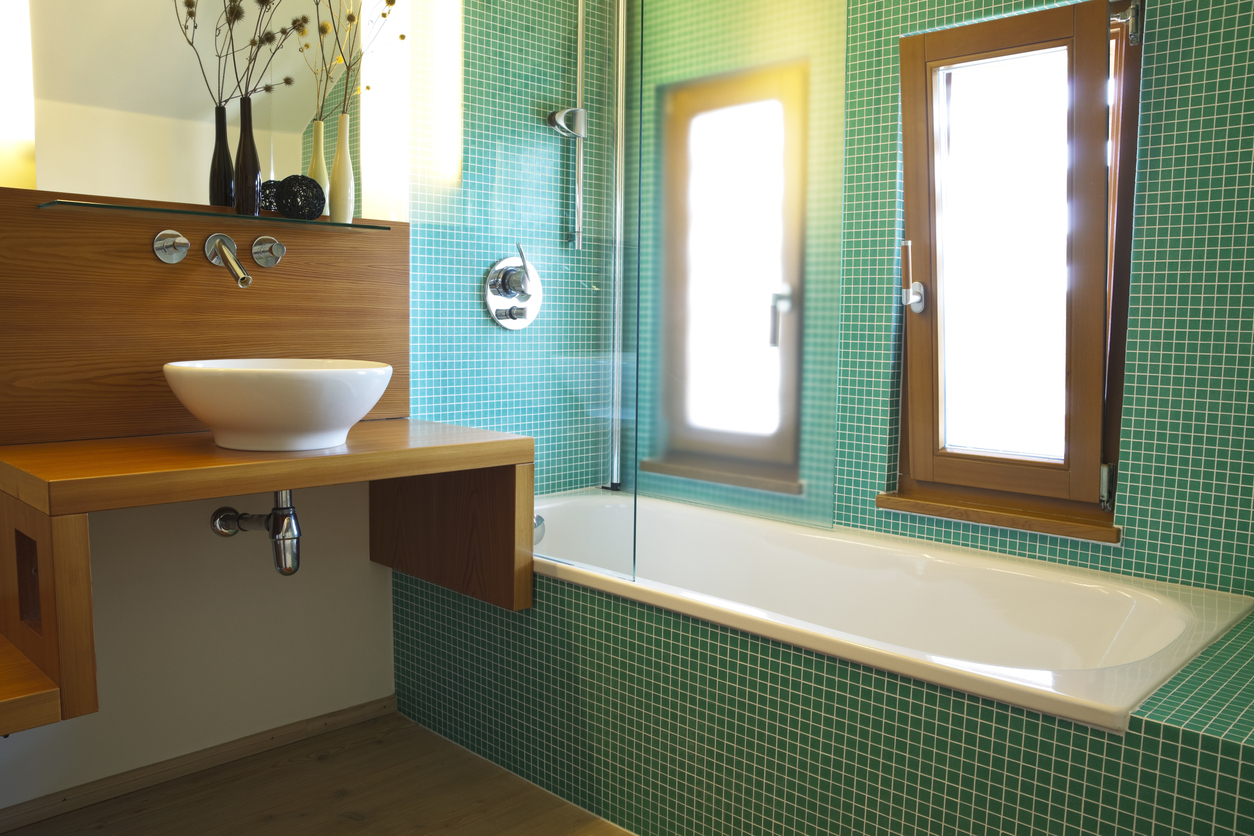 green-tiled-bathtub-next-to-a-wood-counter-with-a-white-basin-sink