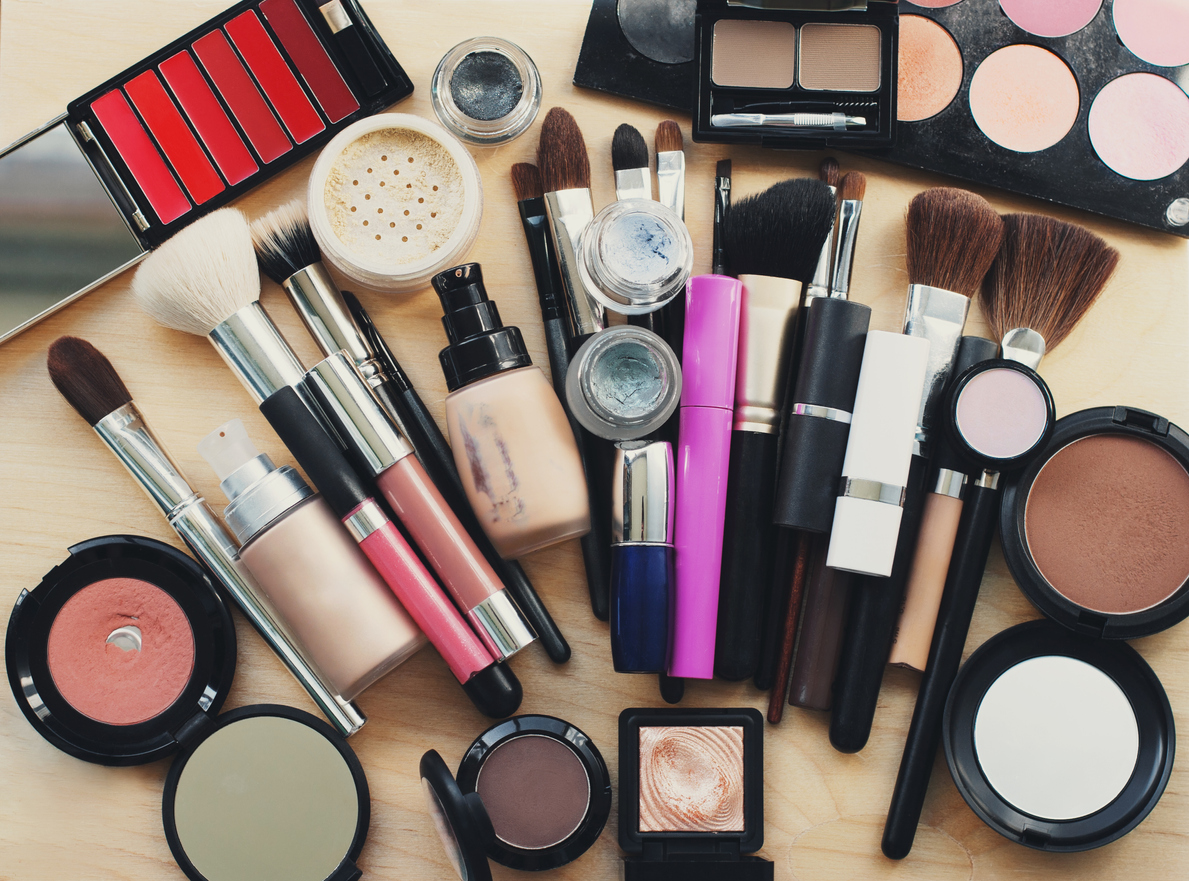 makeup brushes, lipstick, eyeliner and mascara fanned out on counter with powder and other makeup items on display