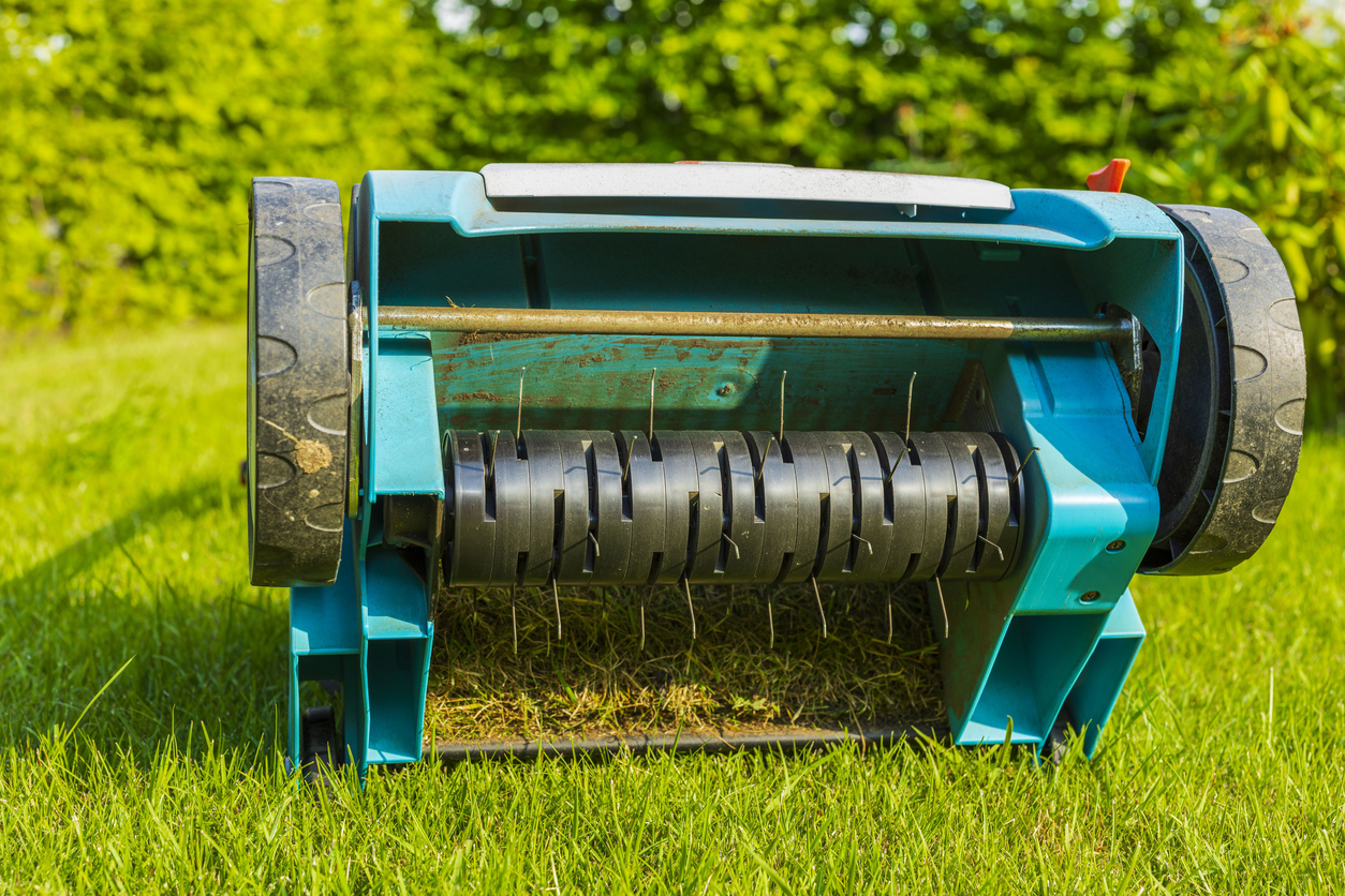 Close up view of electric lawn aerator on green grass isolated. Garden machines concept.