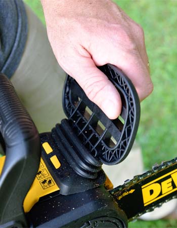 Person's hand holding chain brake on DeWalt 20V chainsaw.