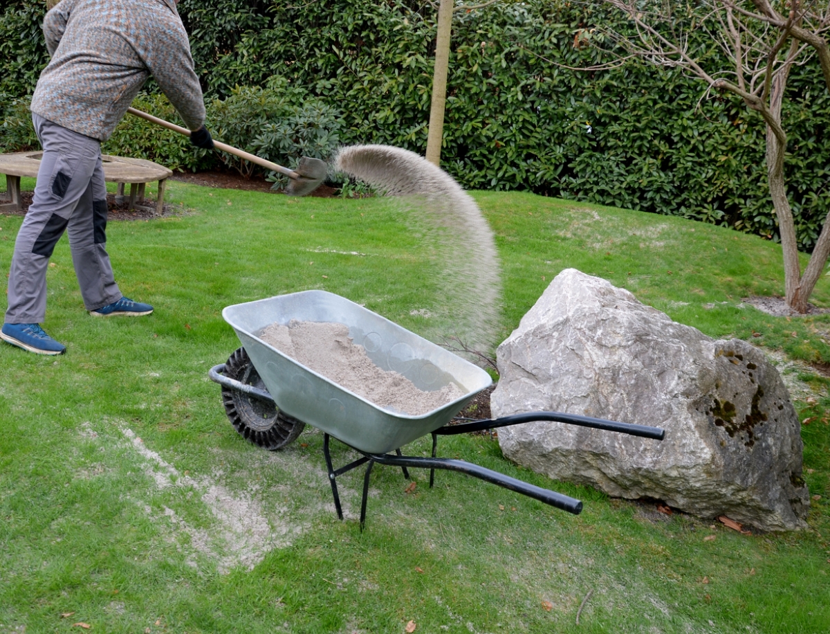 Person shoveling sand on lawn