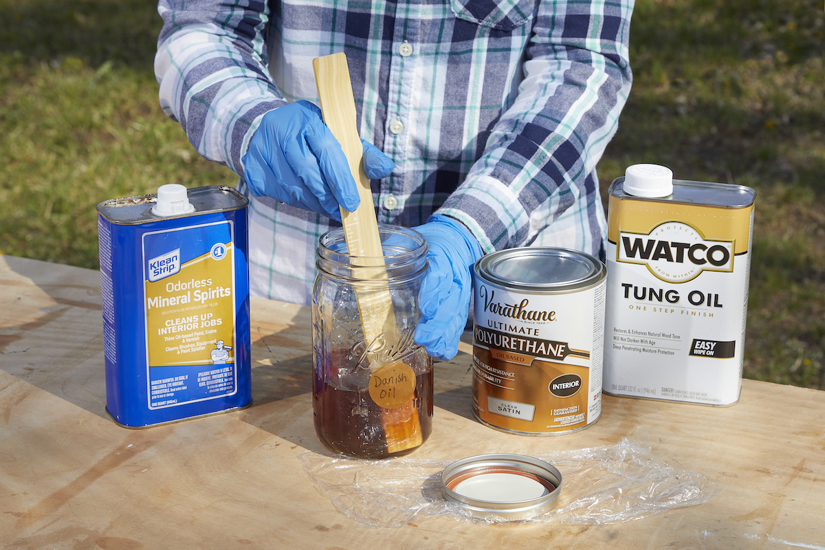 Woman stirs Danish oil with mineral spirits and polyurethane.