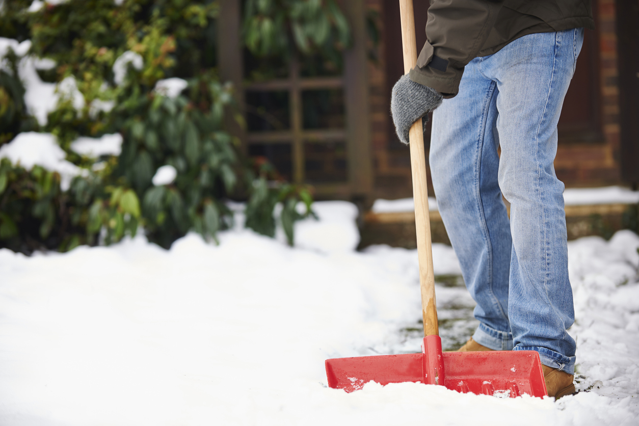 L'huile de coco est utilisée par un homme qui pellette de la neige sur un trottoir près de sa maison