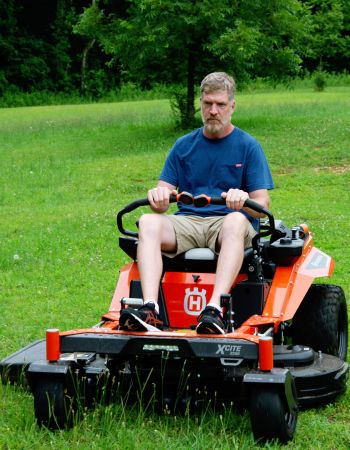 A person mowing their lawn with the Husqvarna XCite 350 zero turn riding mower