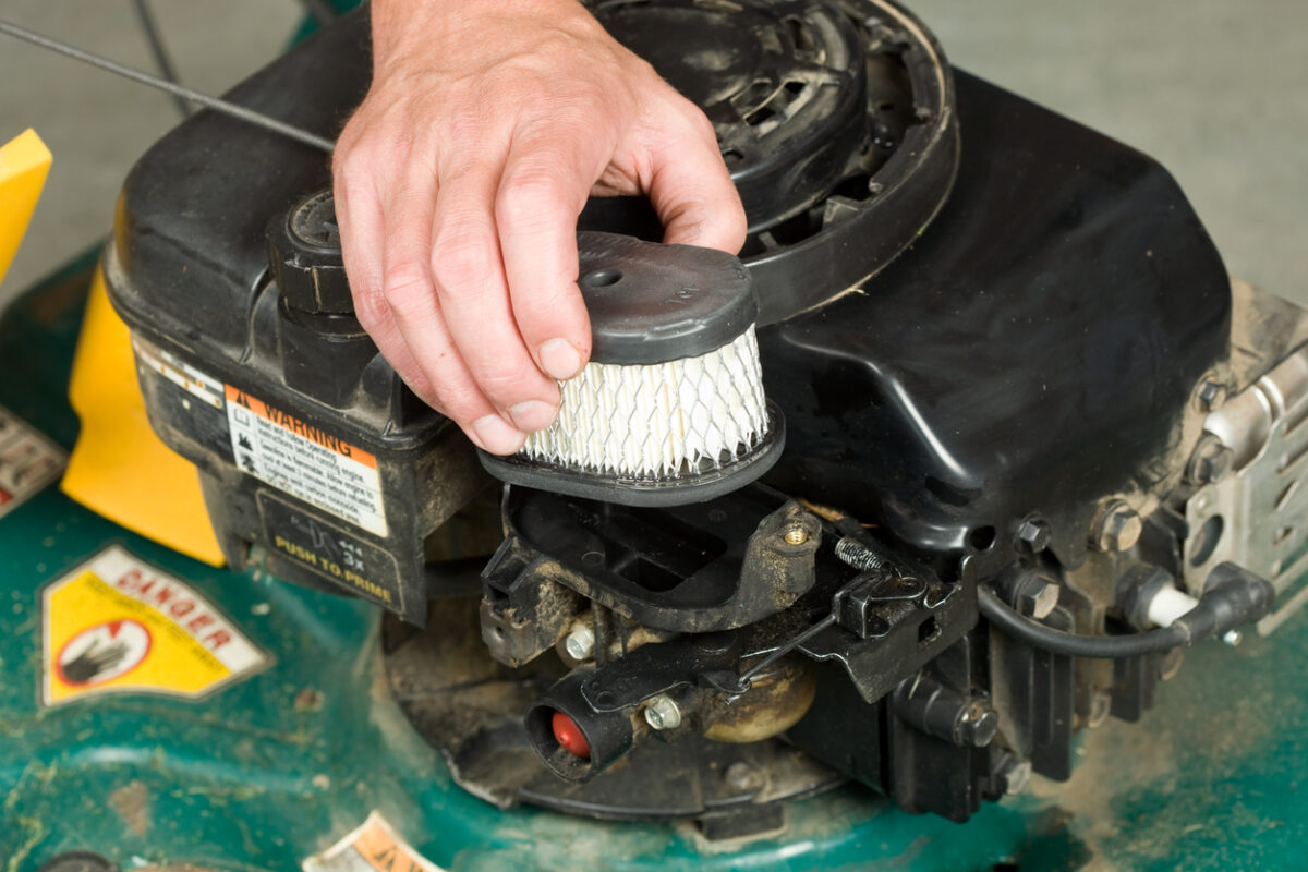 A person is putting a clean air filter inside of a lawn mower.