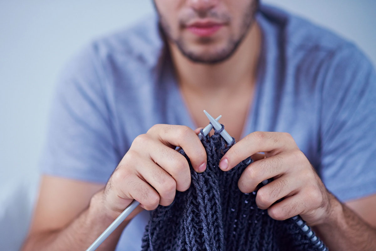 A person knitting a throw blanket for the home.