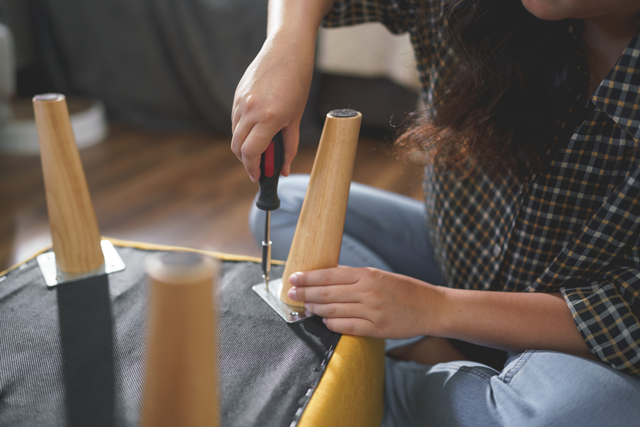 Women tighten screw with screwdriver equipment for repairing leg of chair and assembling furniture.