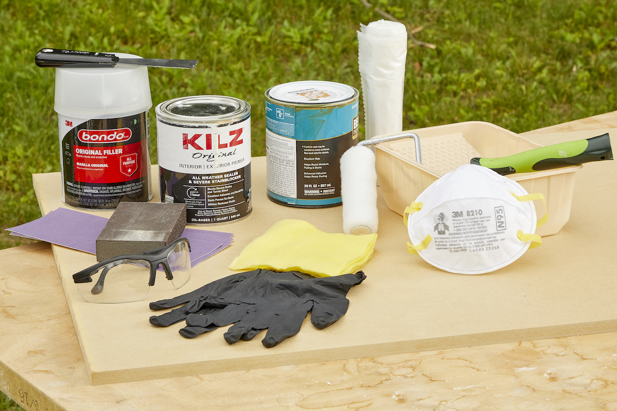 Materials needed for painting MDF spread out on a table, including gloves, primer, paint, and more.