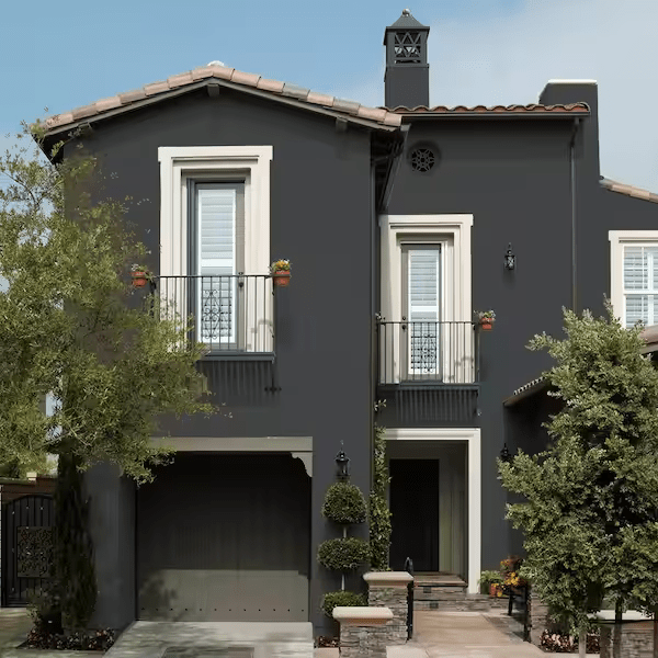 A two story masonry house is painted in a dark grey color.