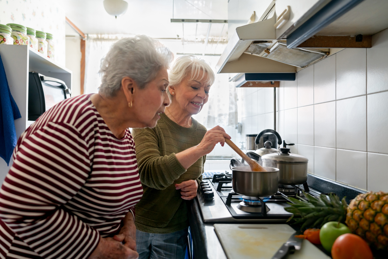 deux femmes âgées cuisinant ensemble sur un fourneau dans une cuisine