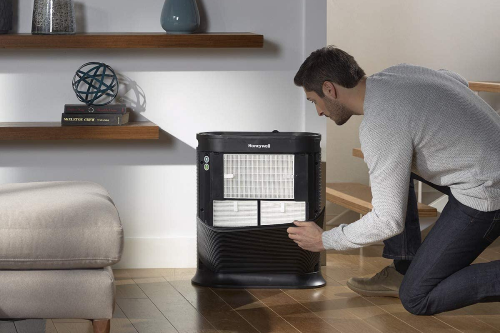 A person kneels down to make an adjustment to the best air purifier for mold option