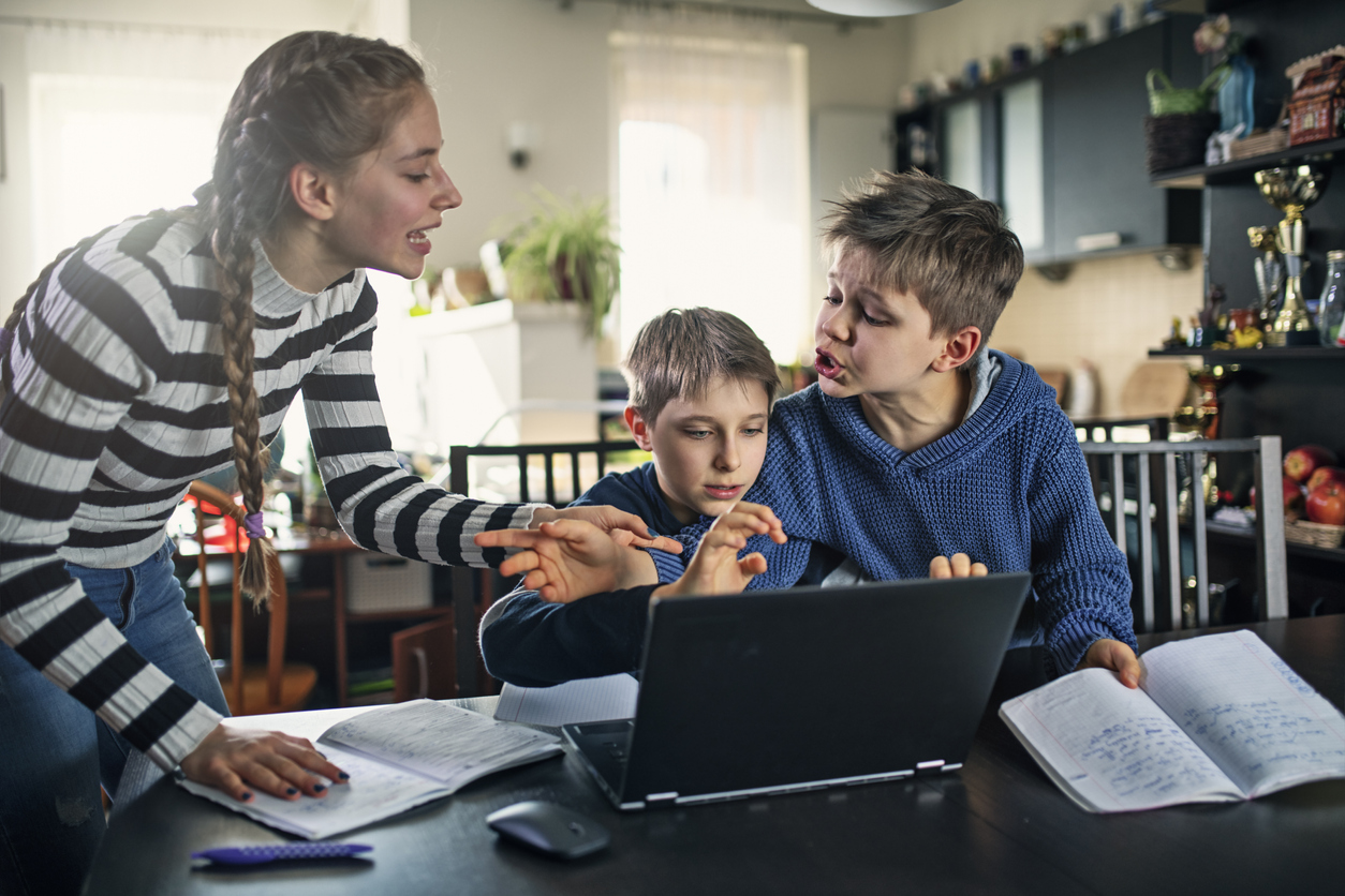 trois frères et sœurs au bureau à domicile se disputent à propos d'un ordinateur portable