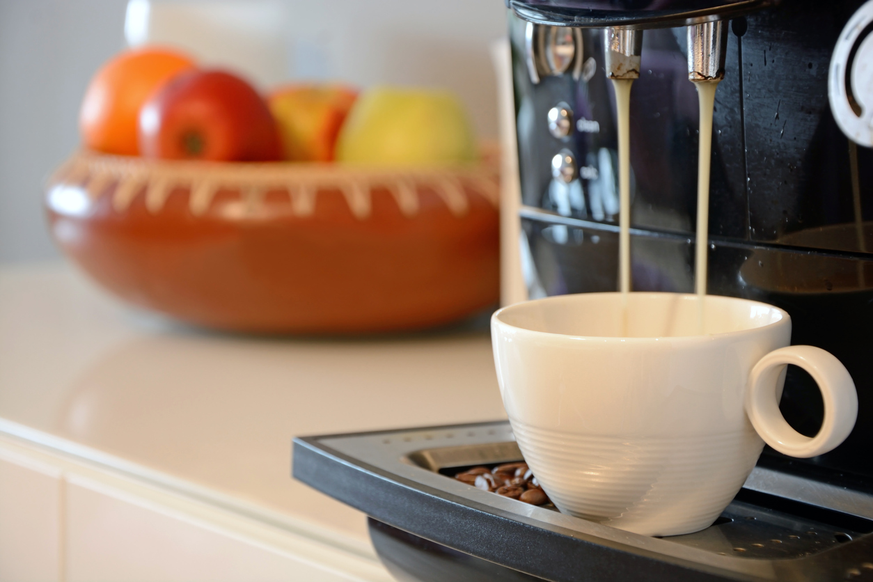 Espresso machine dispensing into a small white espresso cup (demitasse)