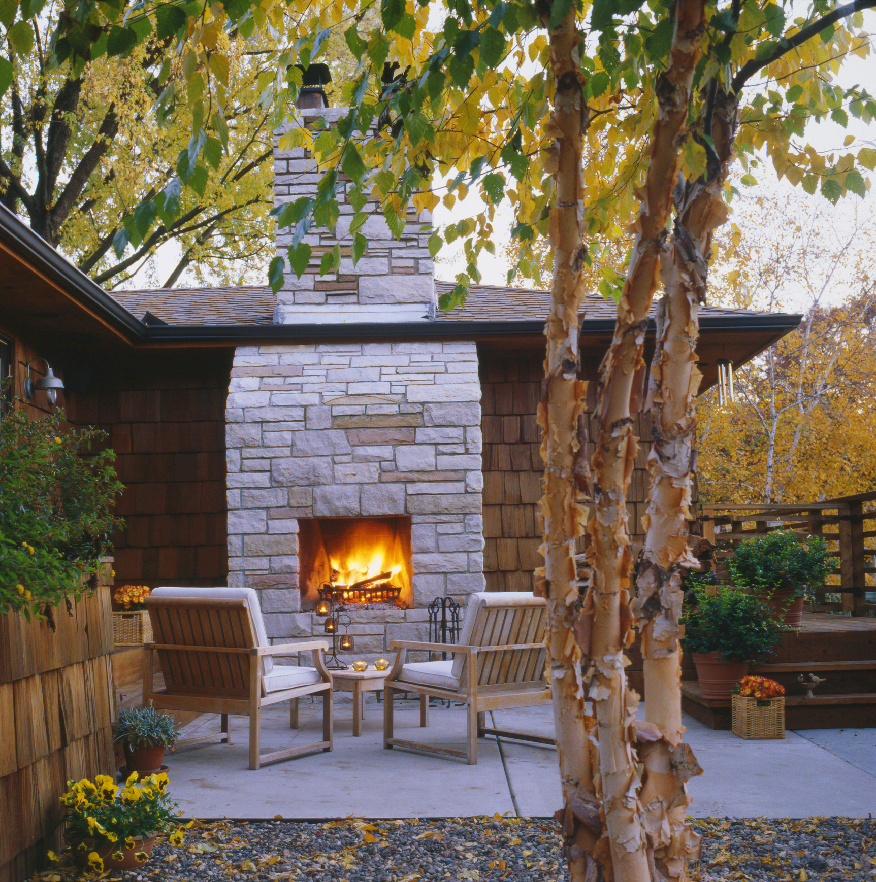 Patio with fire burning in outdoor fireplace during autumn.