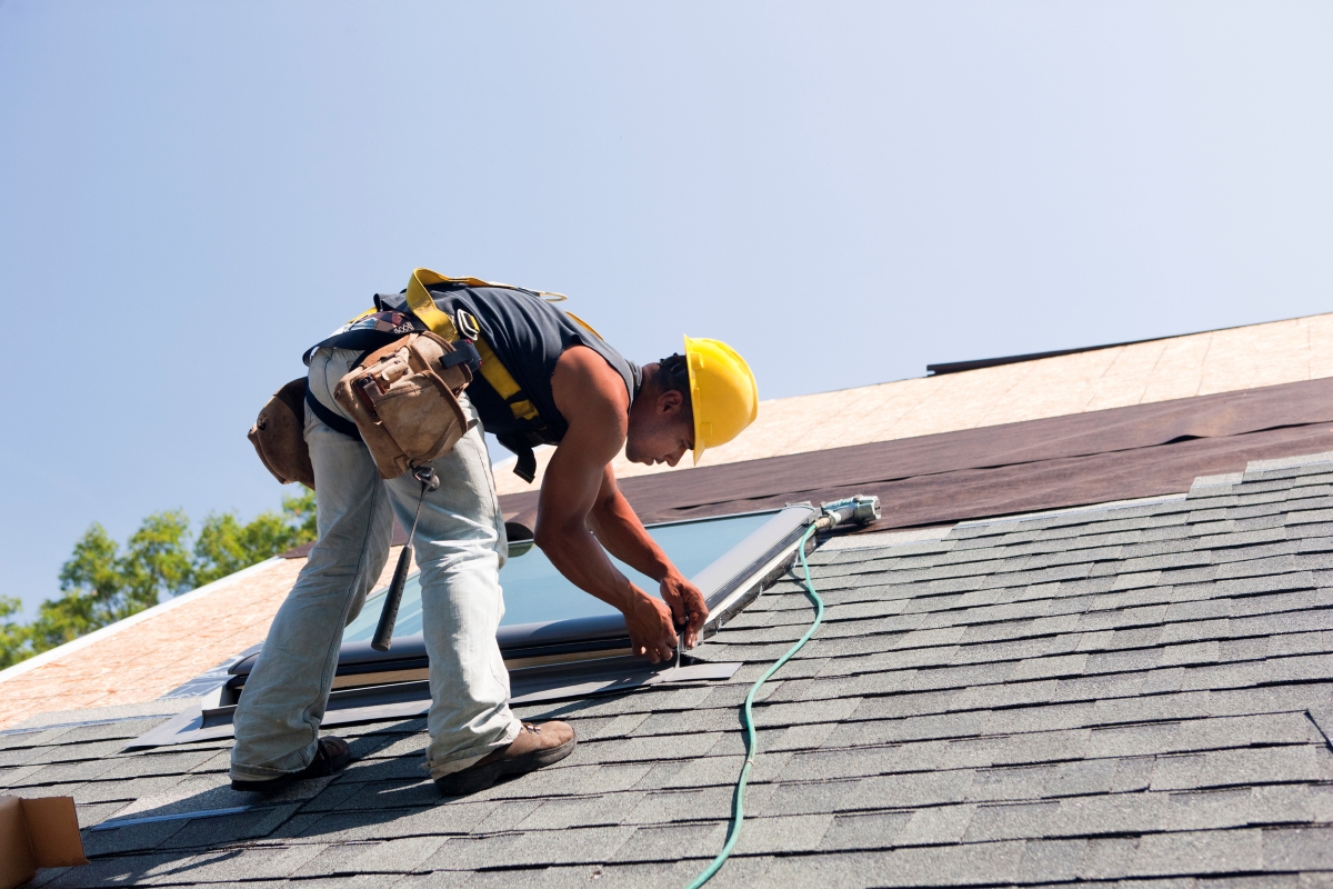 A roofer is finishing the installation around the skylight.