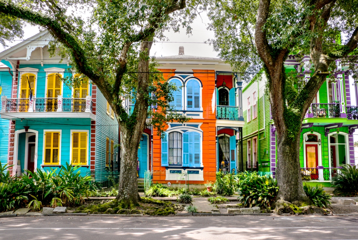 Maisons colorées avec de grands arbres devant.