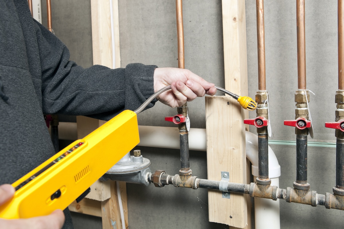 A plumber checking for gas leaks inside an old home during renovation.