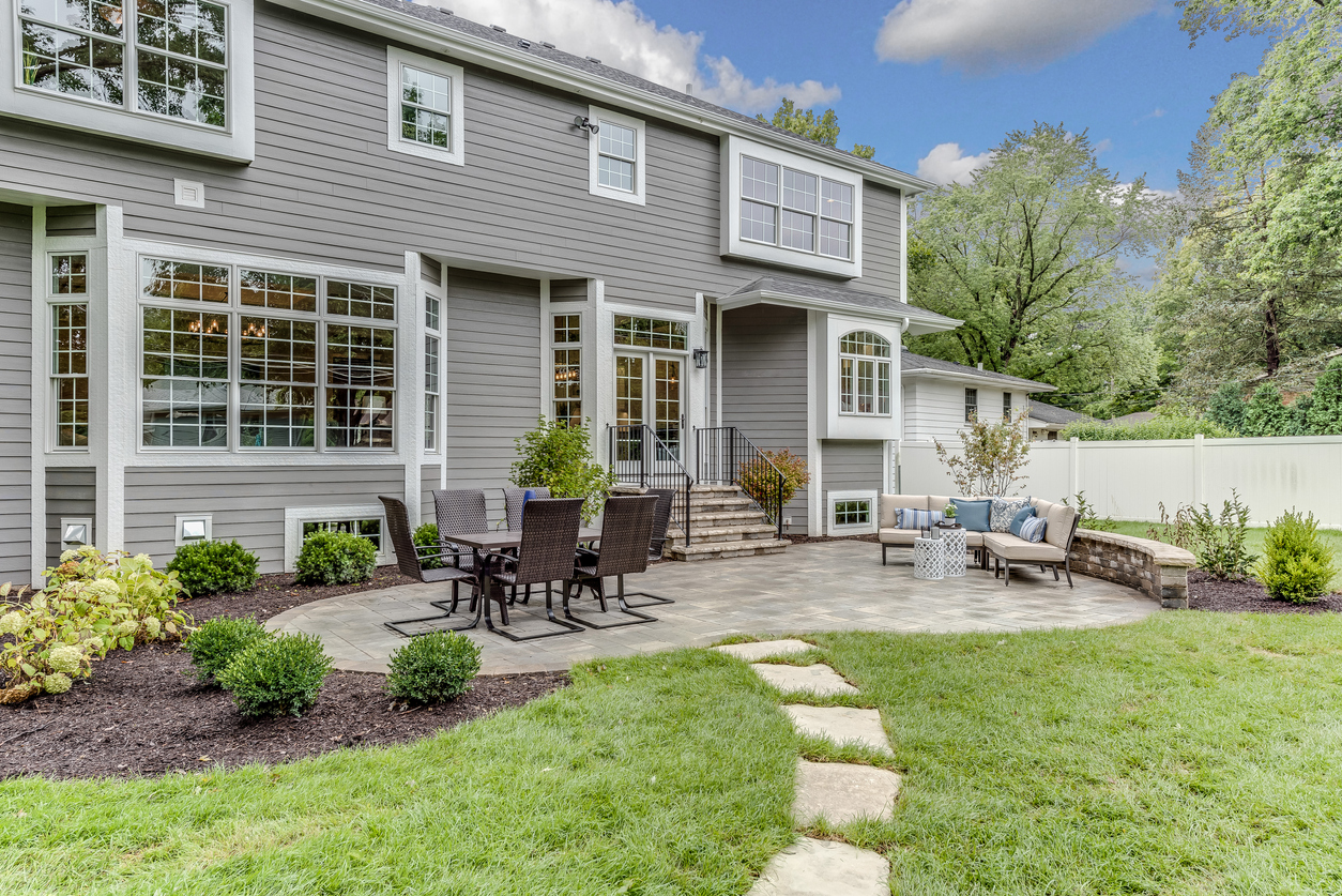 Une maison grise avec un patio en pavés.