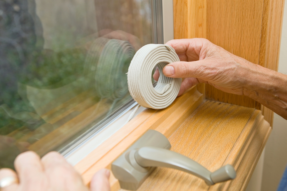 Person adding weatherstripping around window