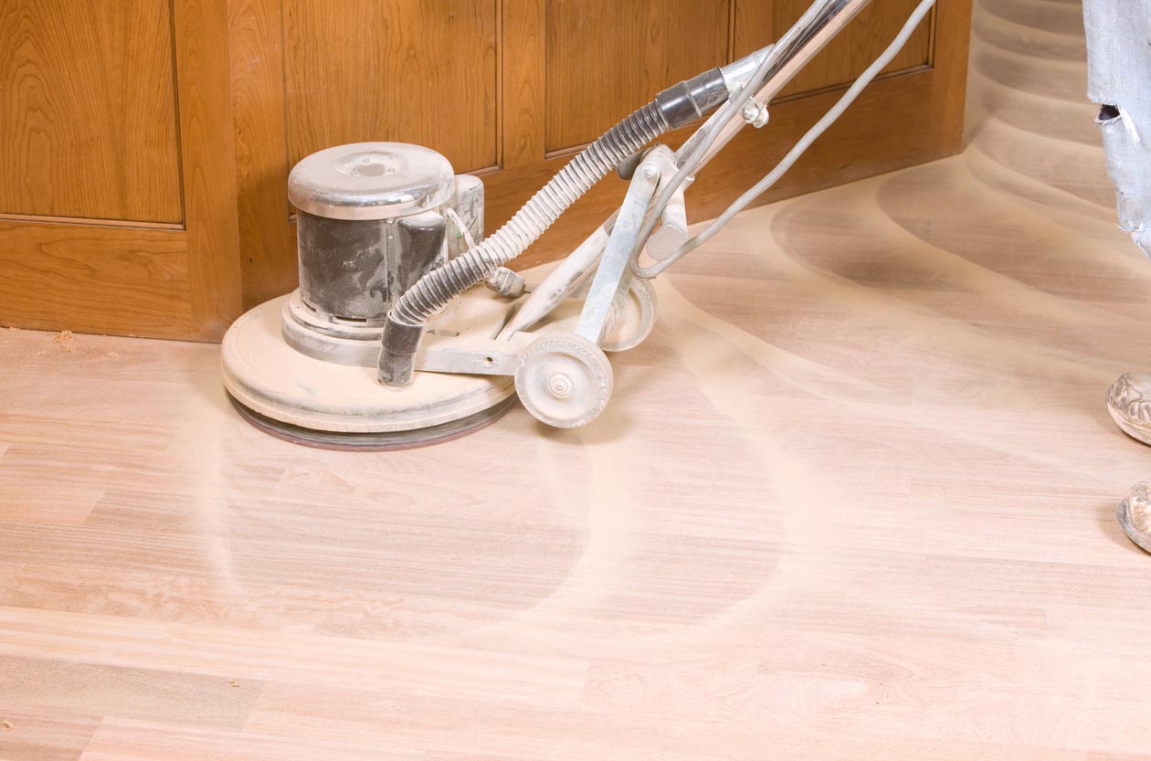 A floor sanding machine in the process of sanding hardwood floors in a home.