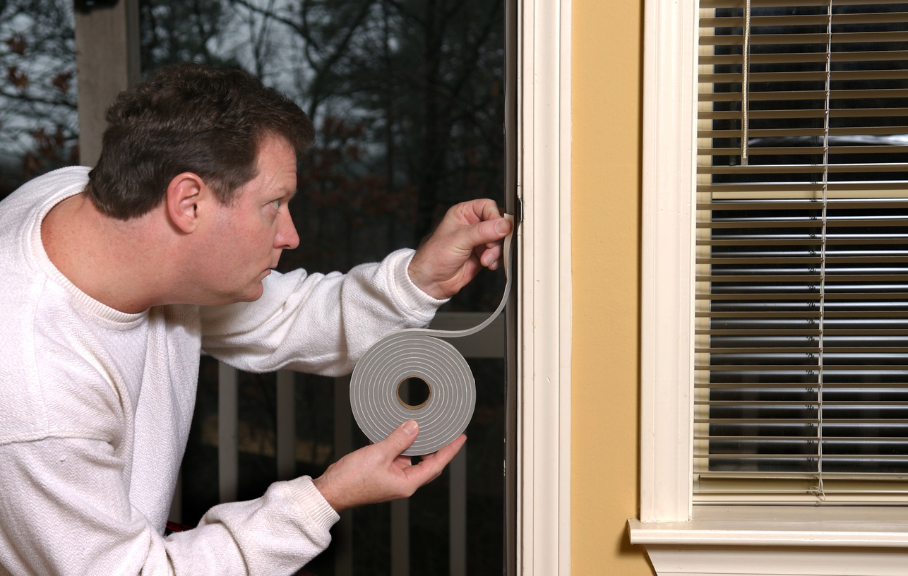 Un propriétaire applique un coupe-froid pour arrêter les fuites d'air autour d'une porte