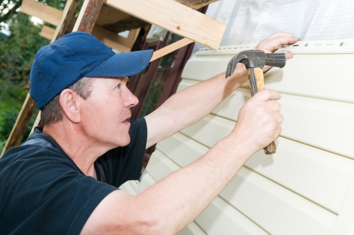 A worker installs siding panels.