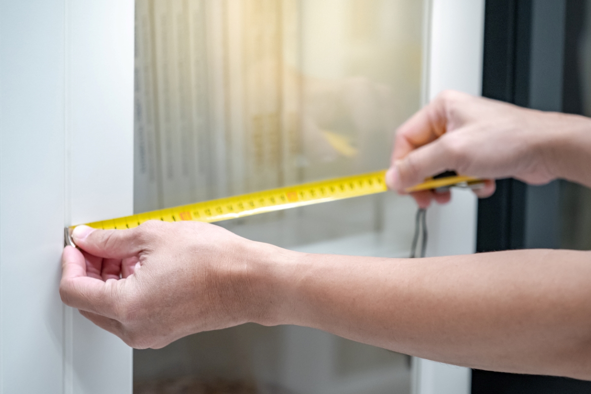 Personne mesurant la porte de l'armoire.