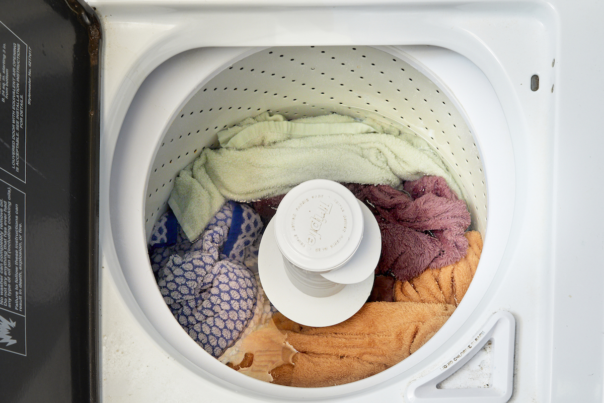 Vue plongeante sur une laveuse à chargement par le haut pleine de linge.