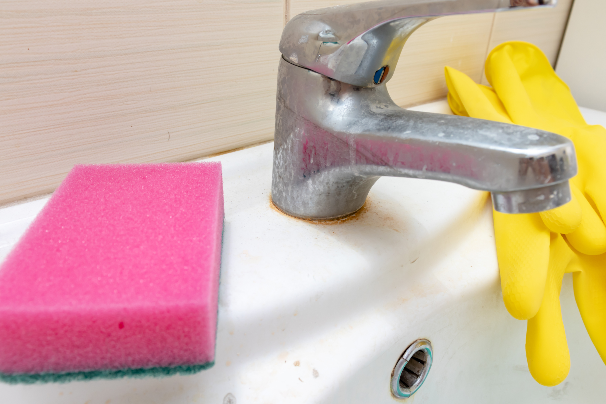 Éponge et gants pour laver le robinet sale avec du calcaire, robinet d'eau calcifié avec du calcaire sur le lavabo de la salle de bain, concept de nettoyage de la maison.