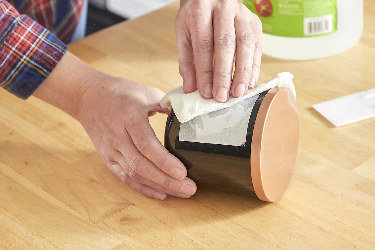 Woman uses vinegar to remove adhesive label from a jar.