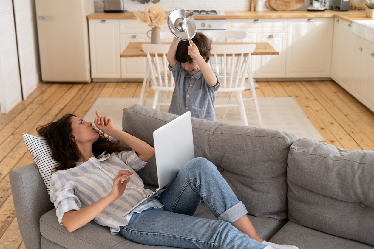 Overwhelmed mom ask son to be silent surfing internet for work. Parent and child on covid lockdown