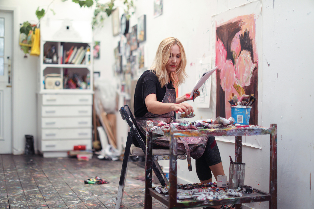 a Mature woman, working on paintings in her home studio.