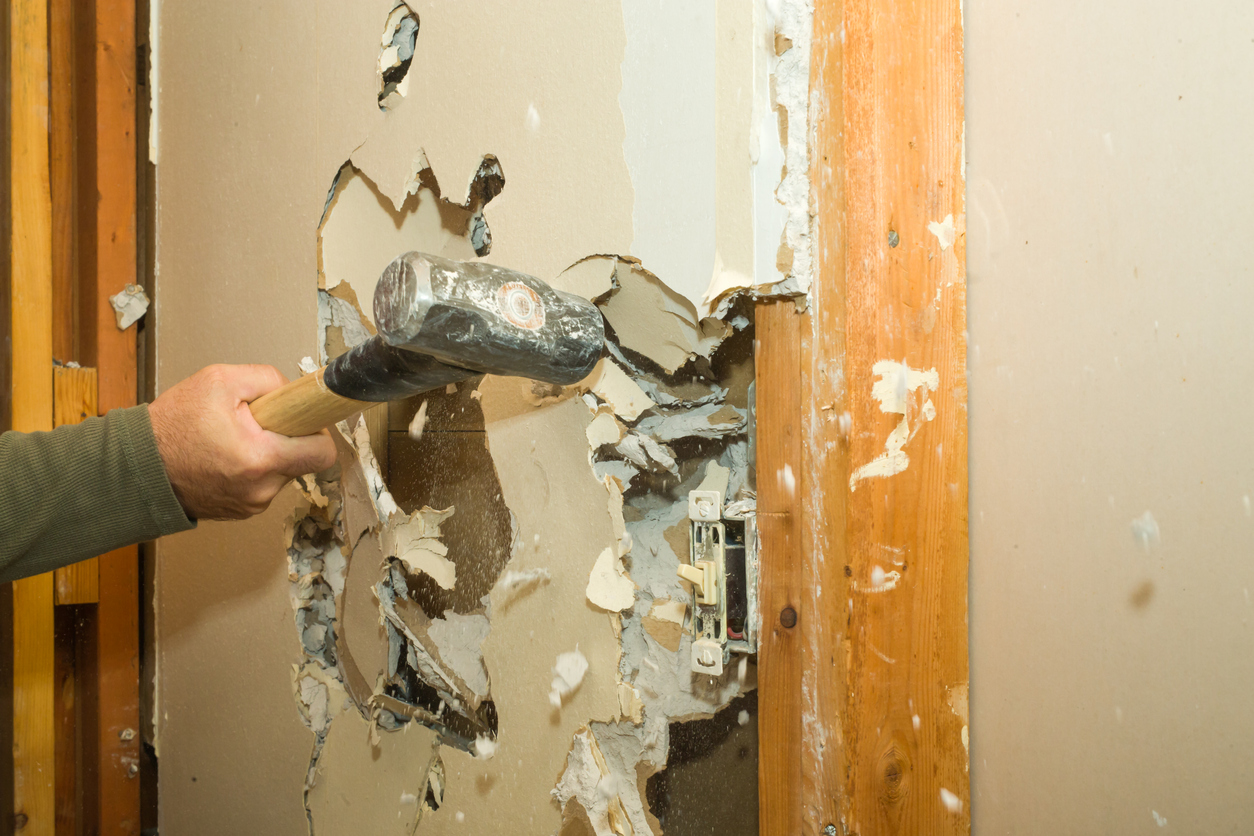 iStock-532531839 walk-in closet storage space demolishing drywall with sledgehammer