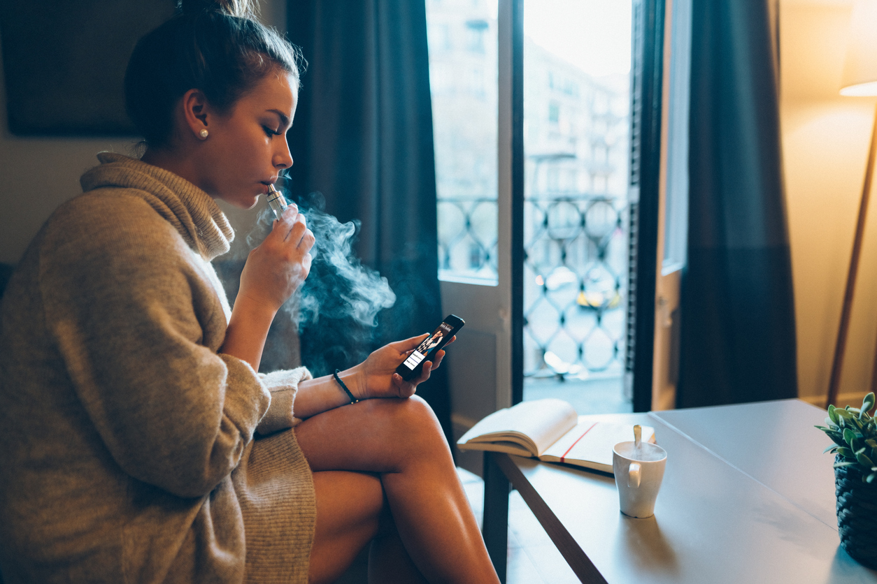 femme fumant à l'intérieur tout en regardant son téléphone