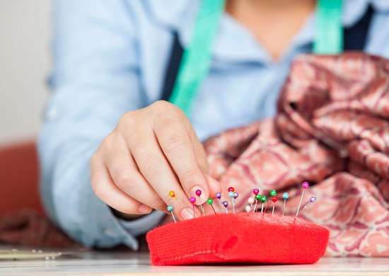 Close up of a woman using a pin cushion