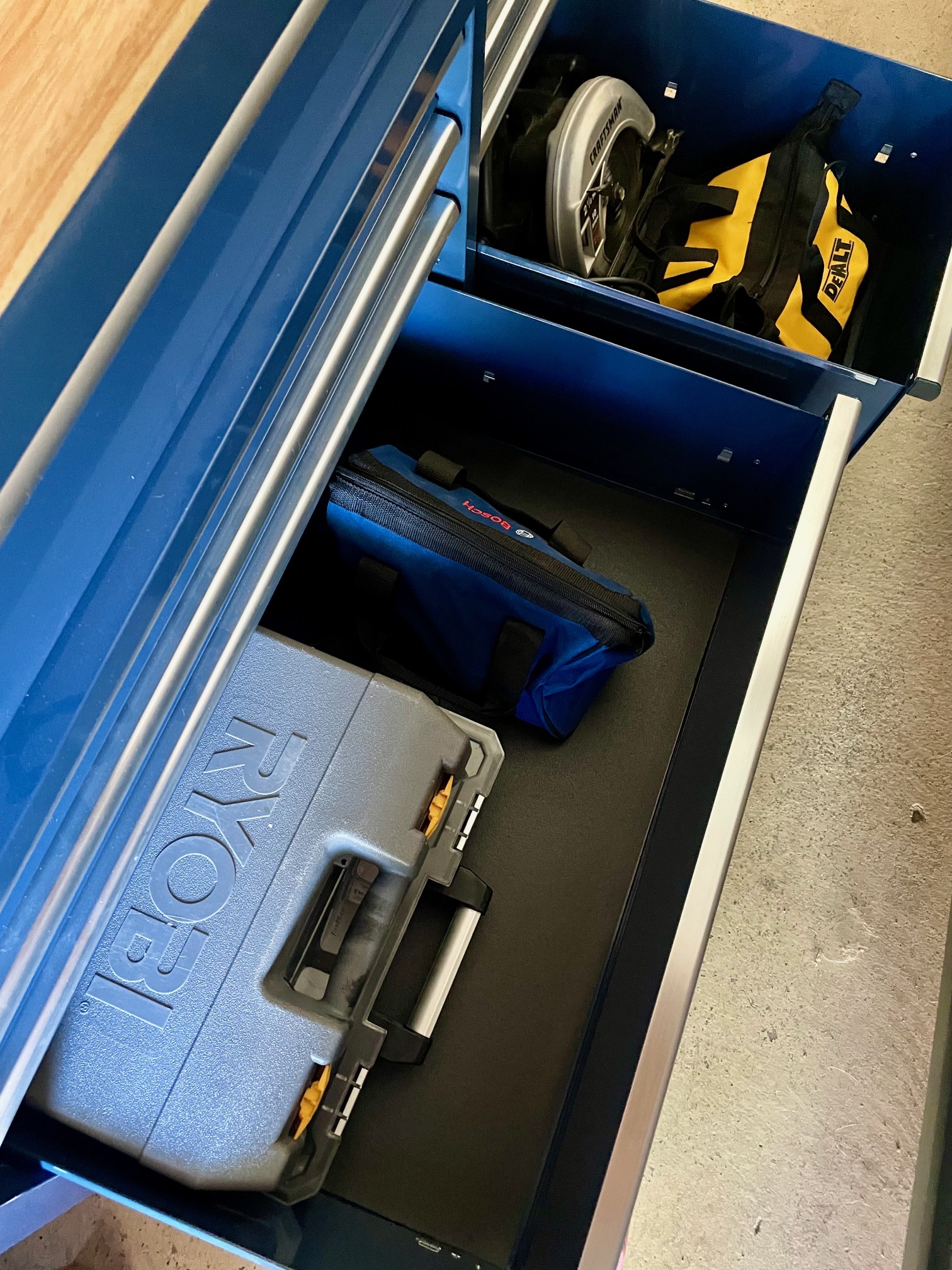 The two large bottom drawers of the Husky Standard Duty 9-Drawer Mobile Workbench Cabinet open to reveal stored power tools.