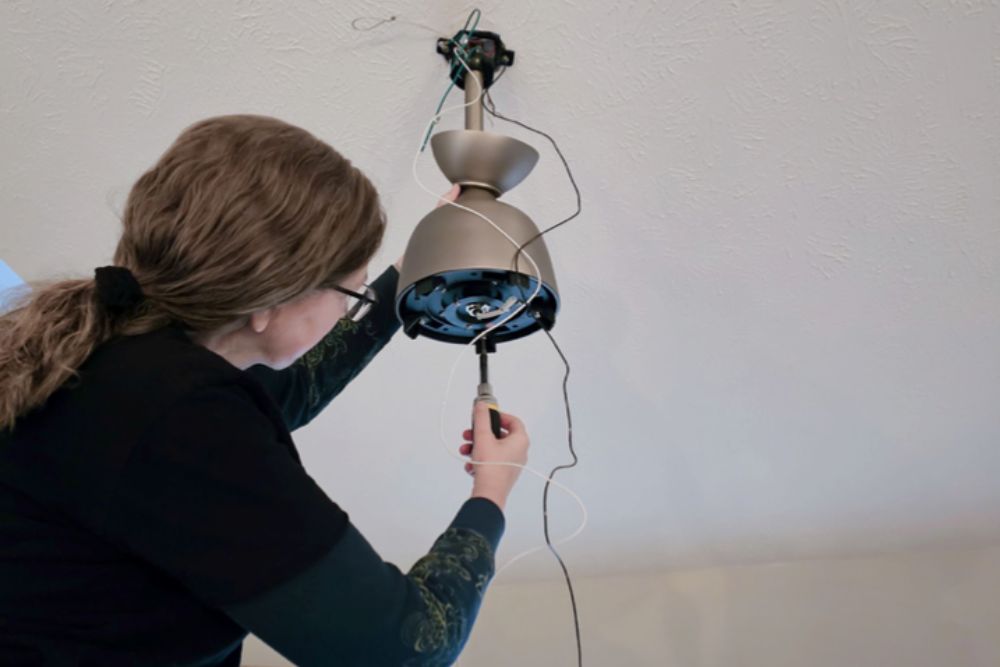 A person installing the base of the Barn by Minka-Aire ceiling fan into their ceiling.